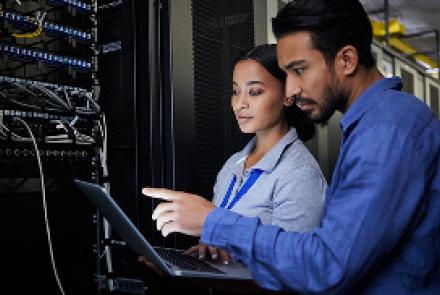 two_it_professionals_in_a_server_room_working_on_a_laptop